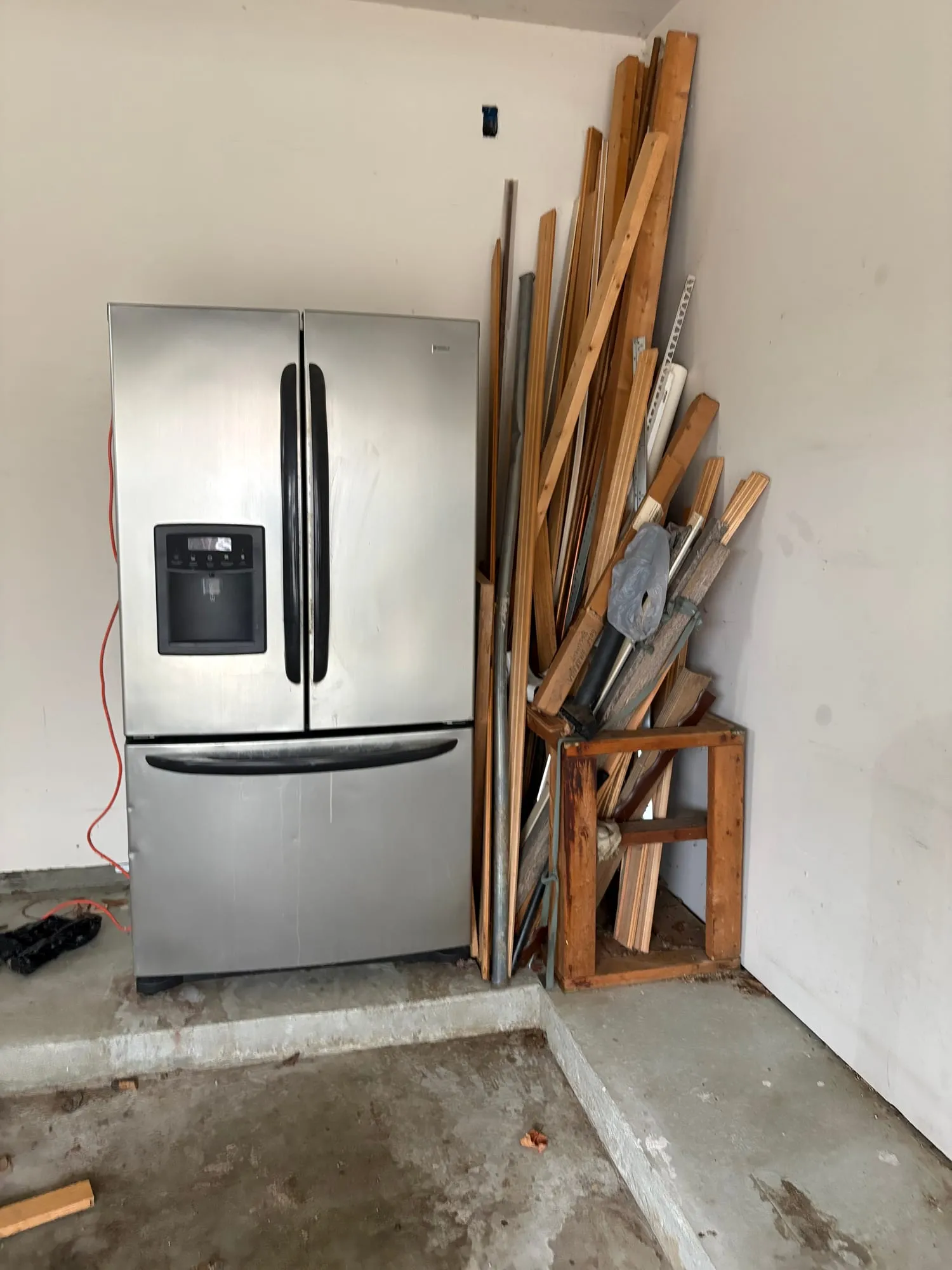 A stainless steel refrigerator set aside for removal in a Metro Detroit garage