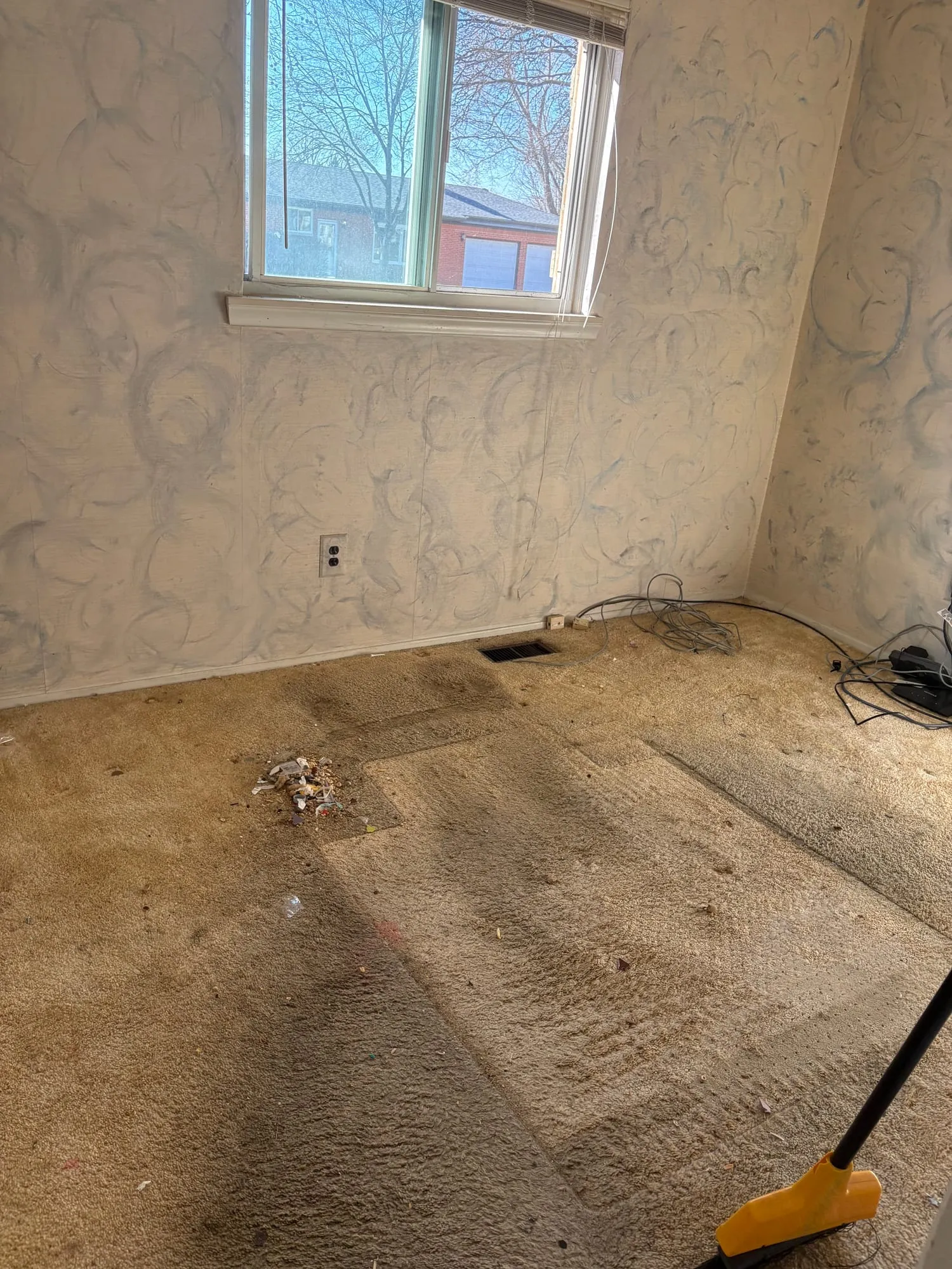 Old carpet torn out of a room, exposing tack strips and bare subfloor