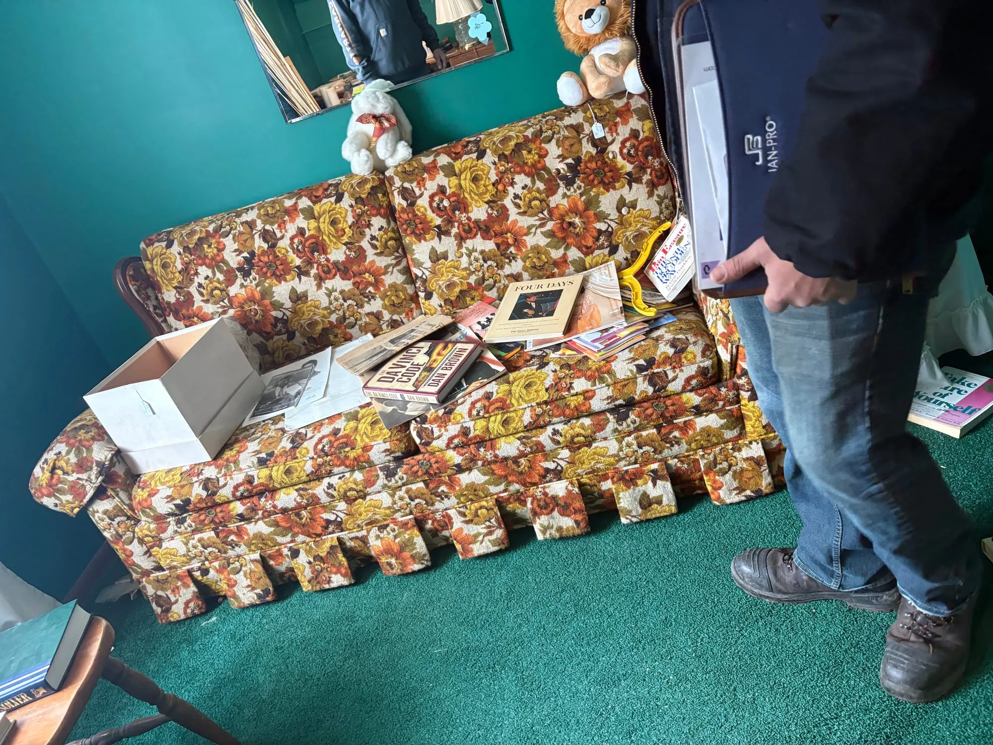 Penguin Junk Removal crew member lifting an old floral couch out of a living room