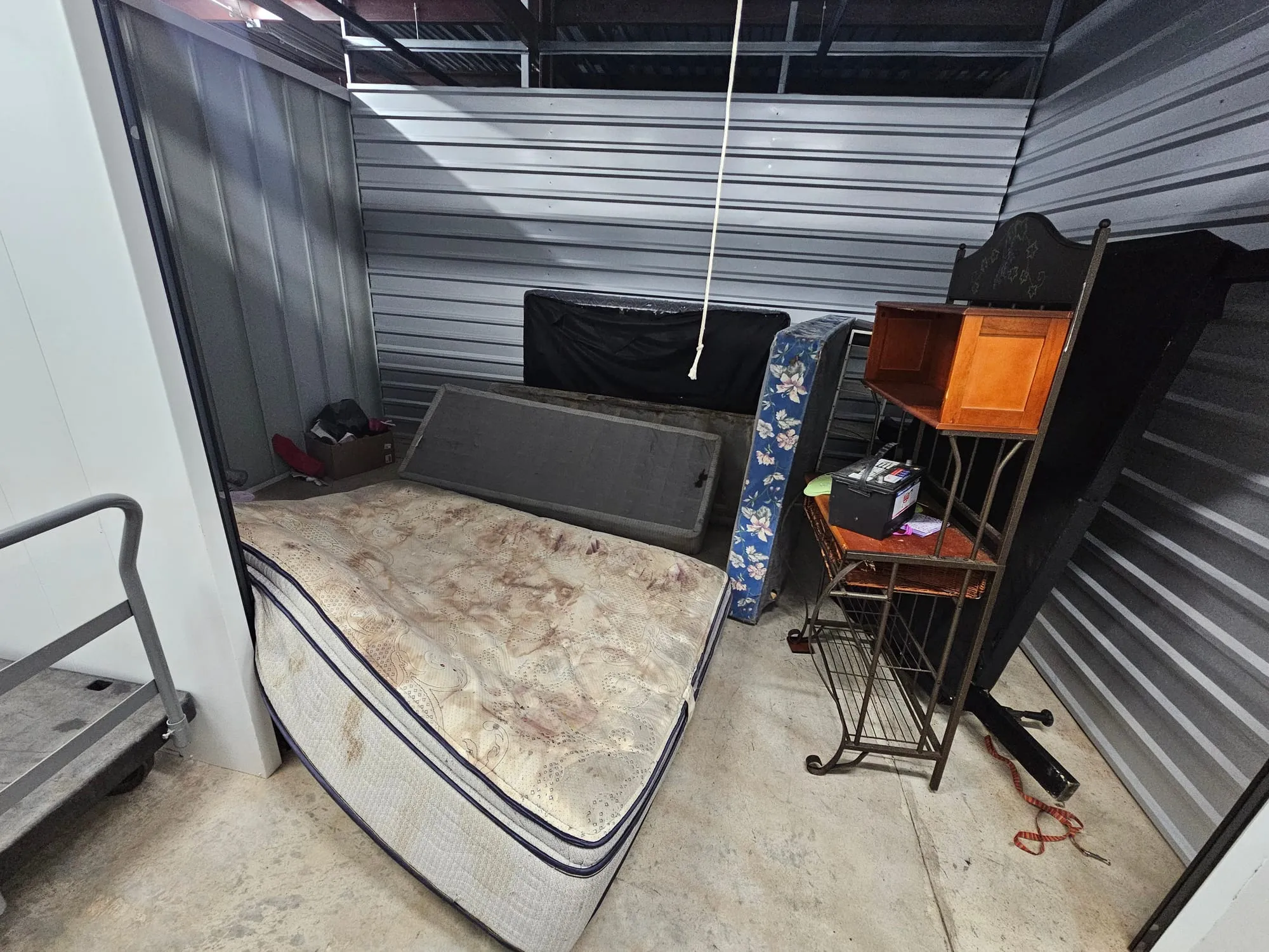 A mattress, chair and desk stacked in a storage unit awaiting removal