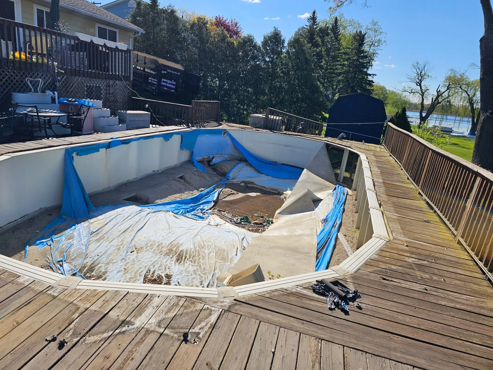 Above-ground pool being torn out with the surrounding deck exposed