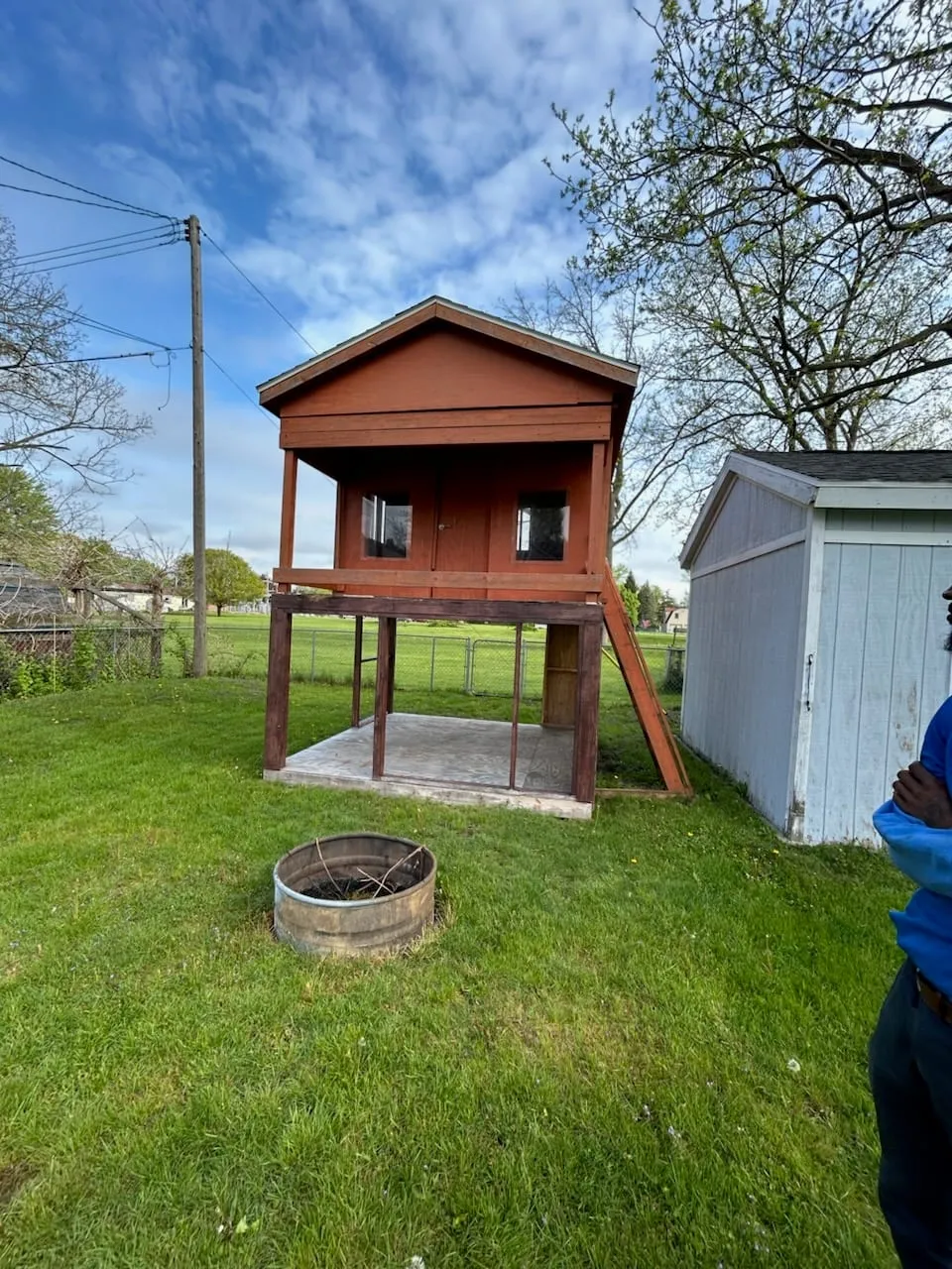 A raised red playhouse and shed on a Metro Detroit lawn before removal