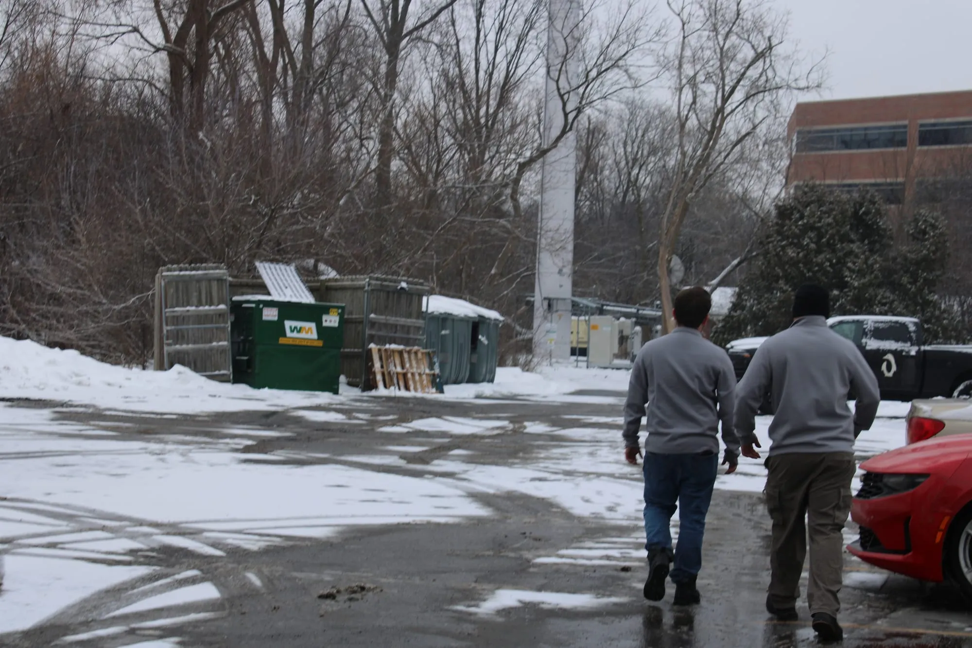 Penguin Junk Removal crew walking to a commercial job past a row of dumpsters
